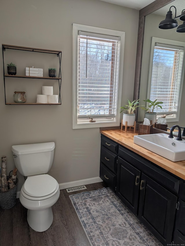 bathroom featuring wood finished floors, toilet, a healthy amount of sunlight, and visible vents