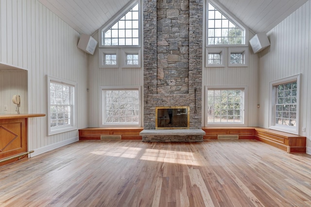 unfurnished living room featuring a fireplace, a wealth of natural light, light hardwood / wood-style flooring, and high vaulted ceiling