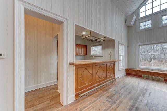 bar featuring hardwood / wood-style floors, baseboards, visible vents, and lofted ceiling