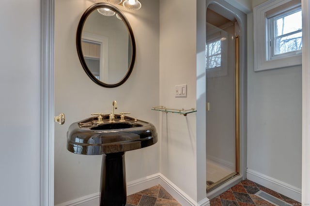 bathroom with stone finish floor, a shower stall, visible vents, and baseboards