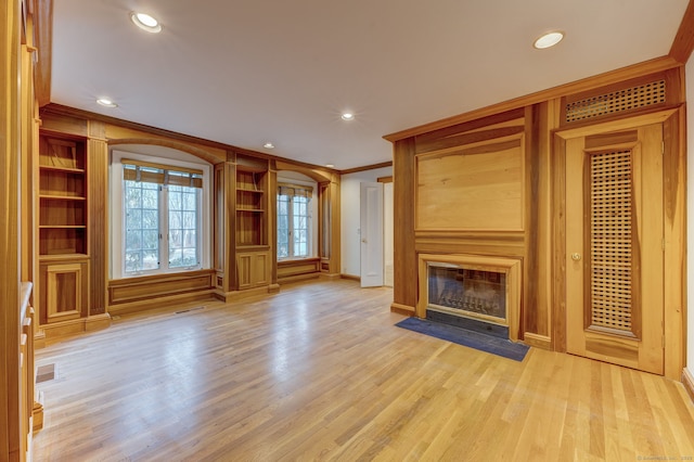 unfurnished living room with light hardwood / wood-style flooring, built in features, and ornamental molding