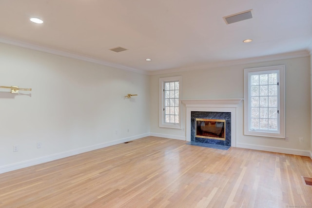 unfurnished living room with light wood-type flooring, ornamental molding, and a high end fireplace