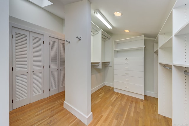 walk in closet with light hardwood / wood-style flooring