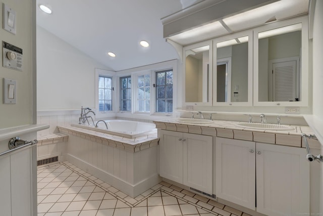 bathroom featuring tiled tub, tile patterned flooring, vanity, and lofted ceiling