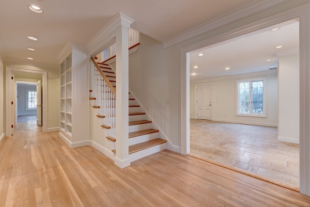 stairs with wood finished floors, baseboards, and ornamental molding