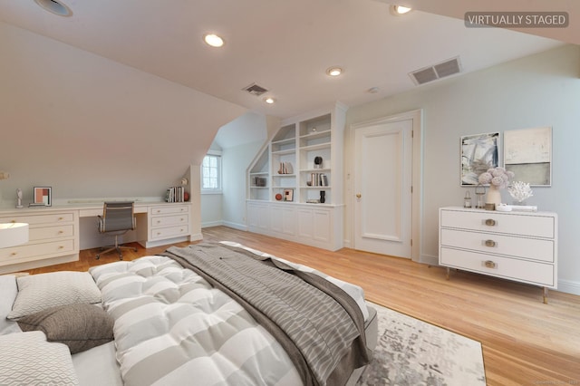 bedroom with built in desk, light wood-type flooring, and lofted ceiling