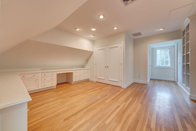 additional living space featuring lofted ceiling, light hardwood / wood-style floors, and built in desk