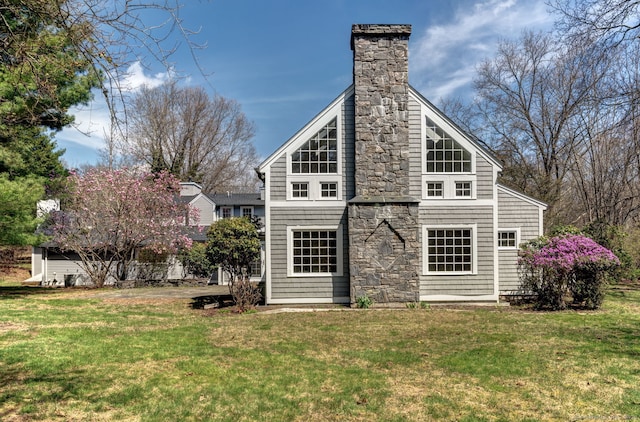 rear view of house with a chimney, stone siding, and a yard