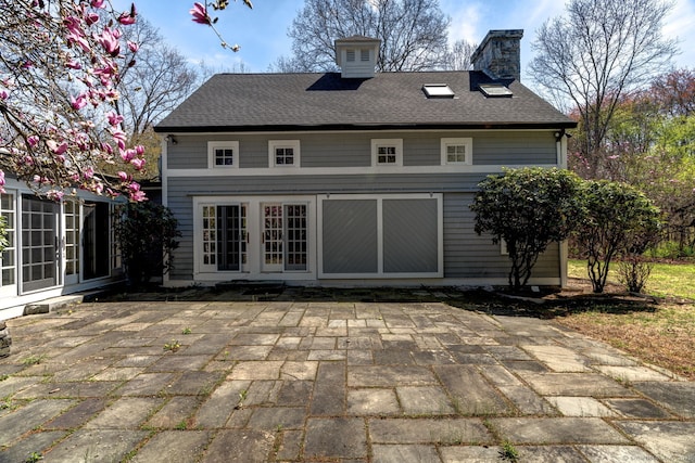 back of property with a chimney, a patio area, a shingled roof, and french doors