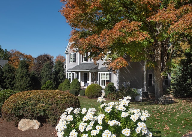 view of side of home with a porch and a yard