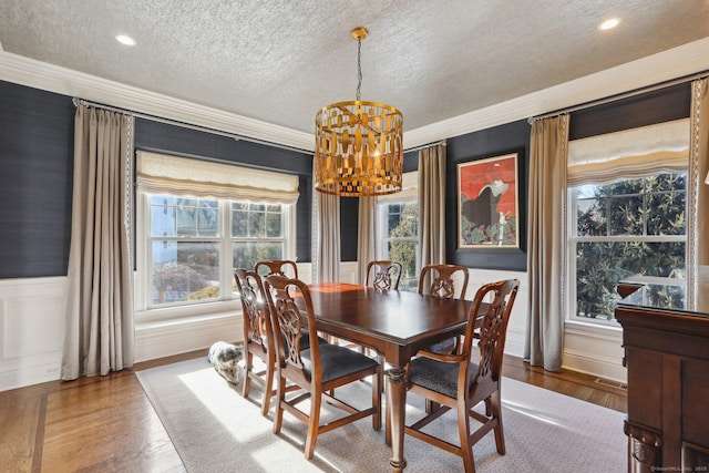 dining area featuring a textured ceiling, ornamental molding, a chandelier, and hardwood / wood-style flooring