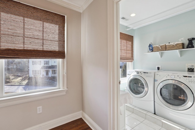 clothes washing area with washing machine and dryer, ornamental molding, and hardwood / wood-style floors