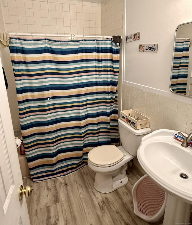 bathroom featuring sink, toilet, hardwood / wood-style flooring, tile walls, and a shower with shower curtain