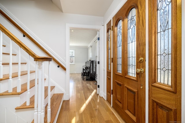 foyer entrance with crown molding and light wood-type flooring