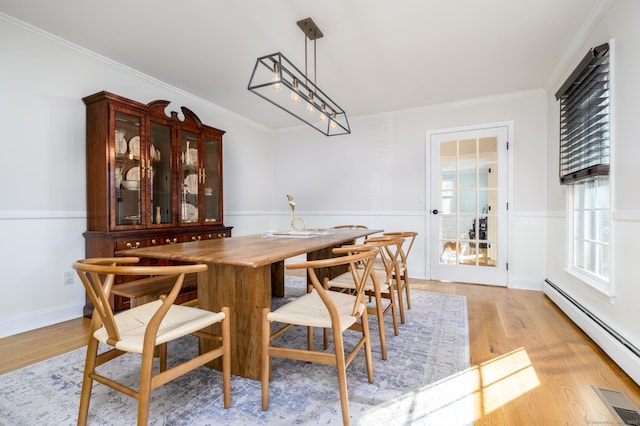 dining area with a baseboard radiator, crown molding, and light hardwood / wood-style floors