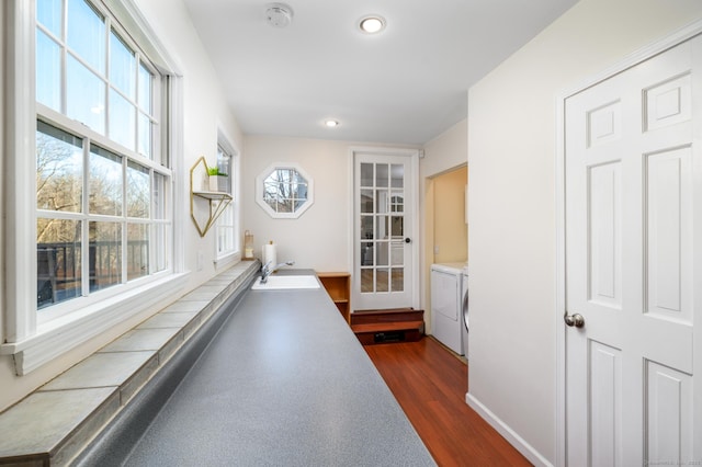 hall with washing machine and clothes dryer, sink, and dark hardwood / wood-style floors