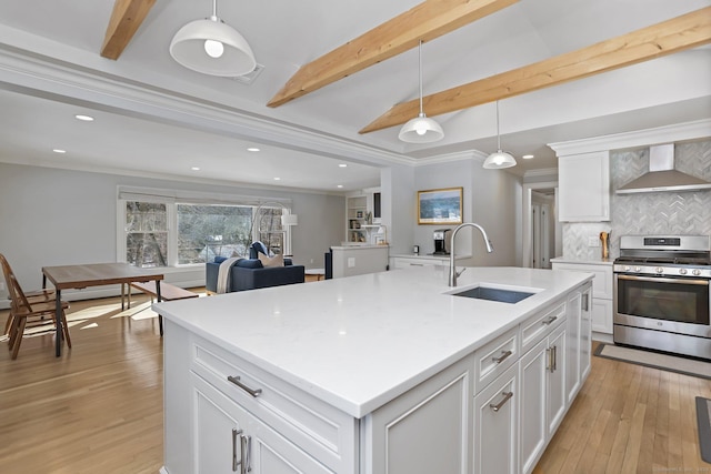 kitchen with decorative light fixtures, gas stove, sink, and wall chimney exhaust hood