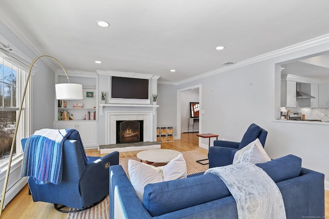 living room featuring crown molding, a brick fireplace, a baseboard heating unit, and light wood-type flooring