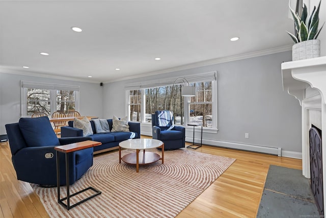 living room with a baseboard heating unit, crown molding, and light wood-type flooring