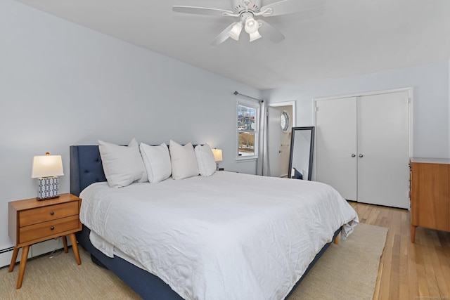 bedroom with light wood-type flooring, ceiling fan, and a closet