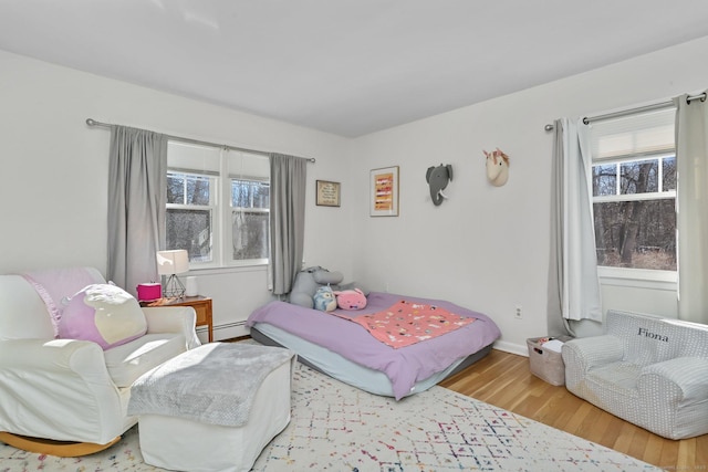 bedroom with hardwood / wood-style flooring and a baseboard heating unit