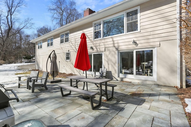 snow covered back of property featuring a patio area