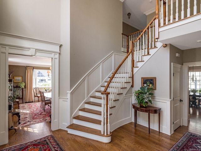 stairs featuring a high ceiling, crown molding, and wood-type flooring