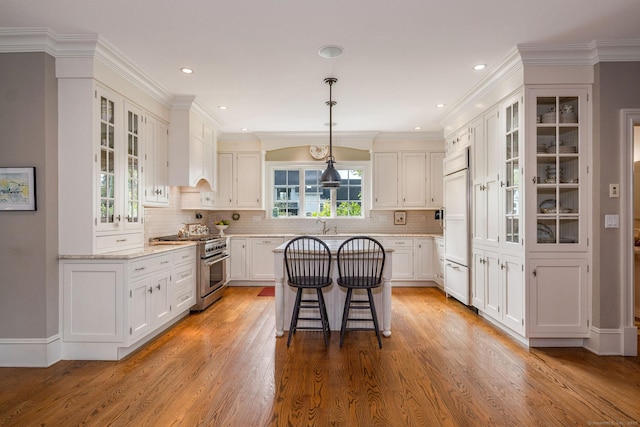 kitchen with pendant lighting, white cabinetry, high end appliances, and a breakfast bar area