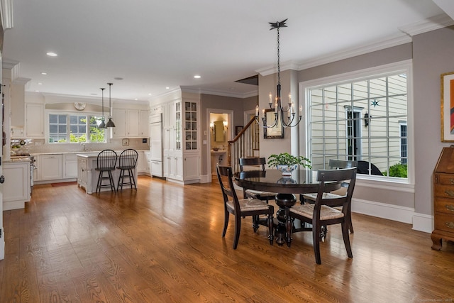 dining area with ornamental molding, a wealth of natural light, a chandelier, and hardwood / wood-style flooring