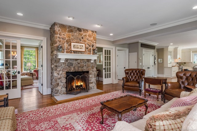 living room with hardwood / wood-style floors, french doors, crown molding, and a stone fireplace