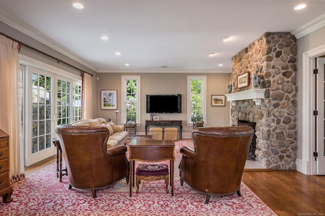 living room featuring wood-type flooring, ornamental molding, french doors, and a stone fireplace