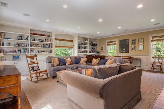 living room featuring built in features, crown molding, and light hardwood / wood-style flooring