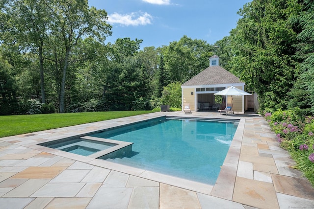 view of swimming pool featuring a patio, a yard, an in ground hot tub, and an outbuilding