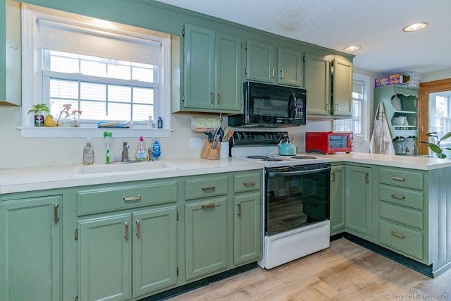 kitchen with electric range oven, kitchen peninsula, sink, green cabinets, and light wood-type flooring