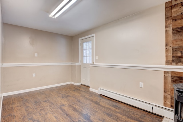 unfurnished room with dark hardwood / wood-style floors and a baseboard heating unit