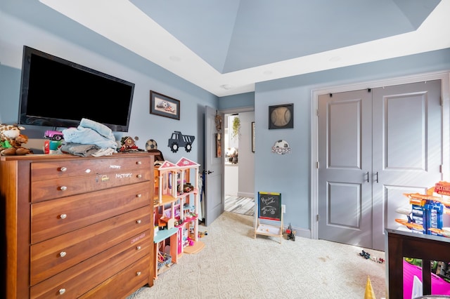 bedroom with light carpet, a raised ceiling, and a closet