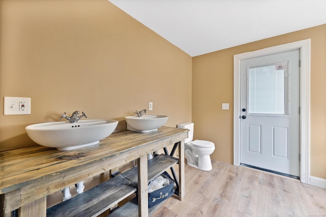 bathroom with lofted ceiling, toilet, wood-type flooring, and vanity