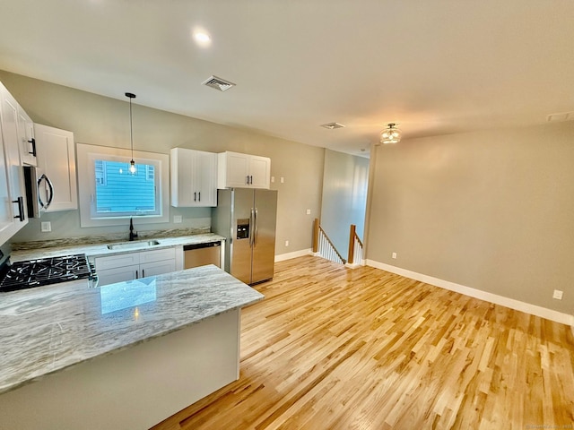 kitchen with white cabinets, sink, light hardwood / wood-style floors, light stone counters, and stainless steel appliances