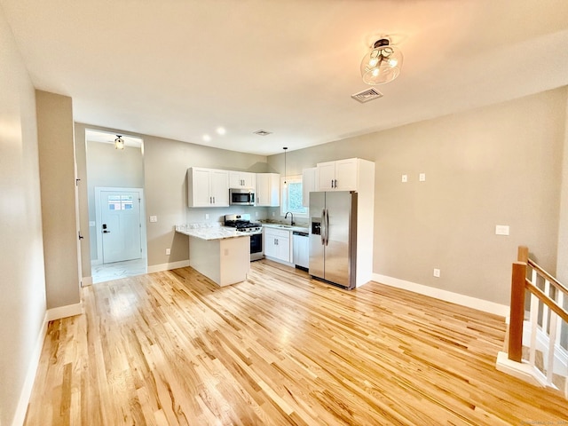 kitchen featuring pendant lighting, white cabinets, sink, appliances with stainless steel finishes, and kitchen peninsula