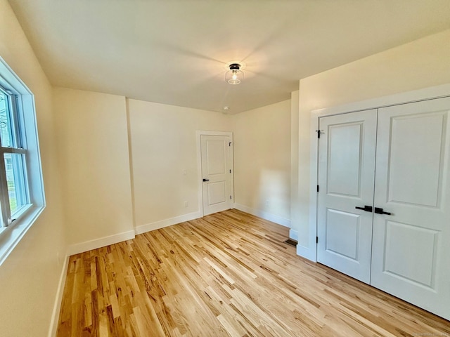 unfurnished bedroom with light wood-type flooring and a closet