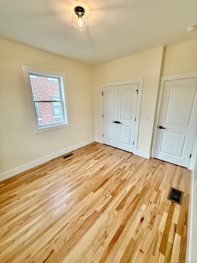 unfurnished bedroom with light hardwood / wood-style flooring and a closet