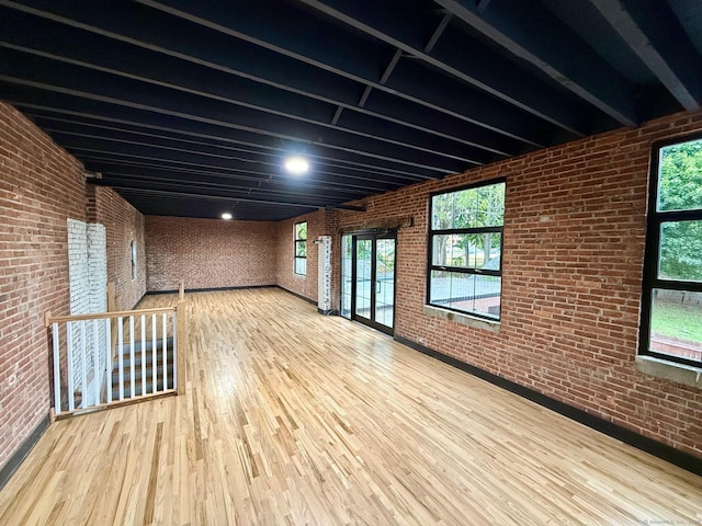 empty room featuring hardwood / wood-style floors and brick wall