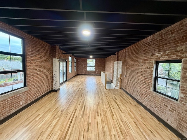 interior space featuring beam ceiling, brick wall, and light wood-type flooring