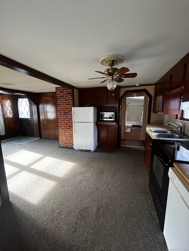 kitchen featuring sink, white fridge, wooden walls, and dark colored carpet