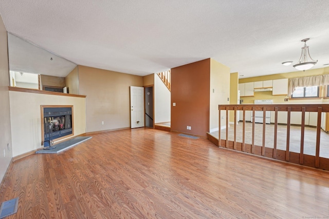 unfurnished living room with light hardwood / wood-style floors and a textured ceiling