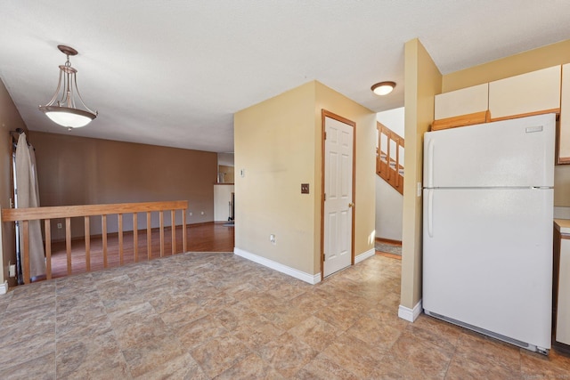 kitchen with white fridge, white cabinetry, and hanging light fixtures