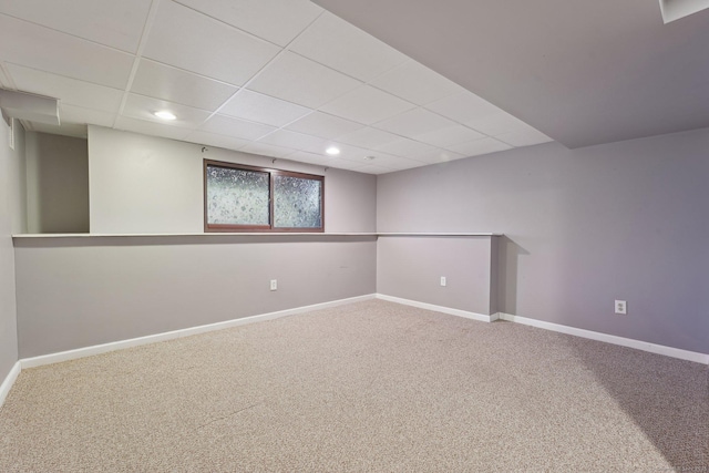 basement with a paneled ceiling and carpet flooring