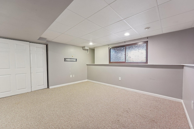 basement featuring a drop ceiling and carpet flooring