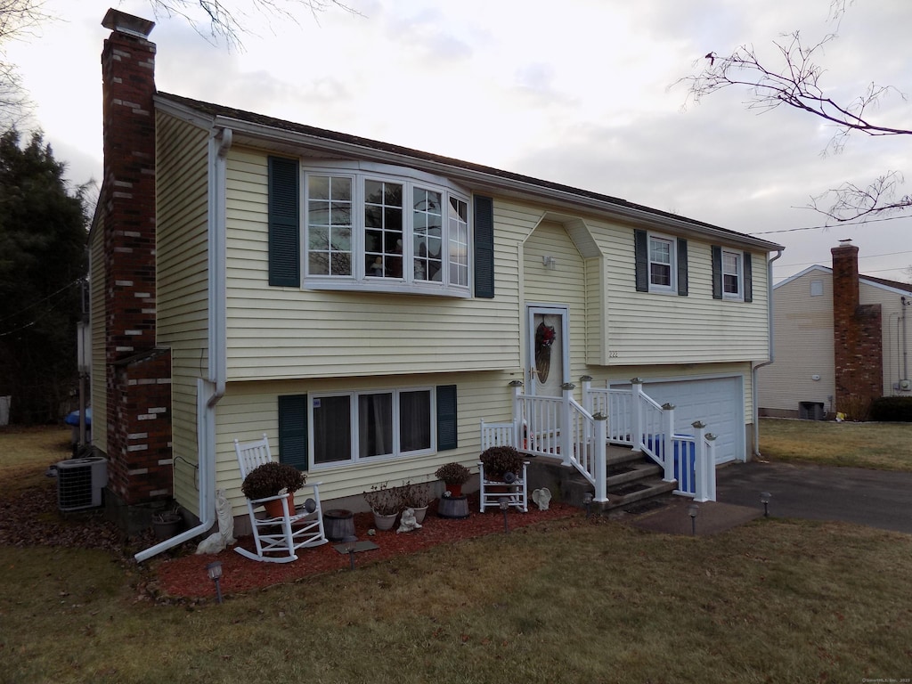 bi-level home with cooling unit, a front yard, and a garage