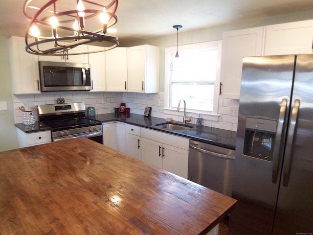 kitchen featuring wooden counters, appliances with stainless steel finishes, white cabinetry, and sink